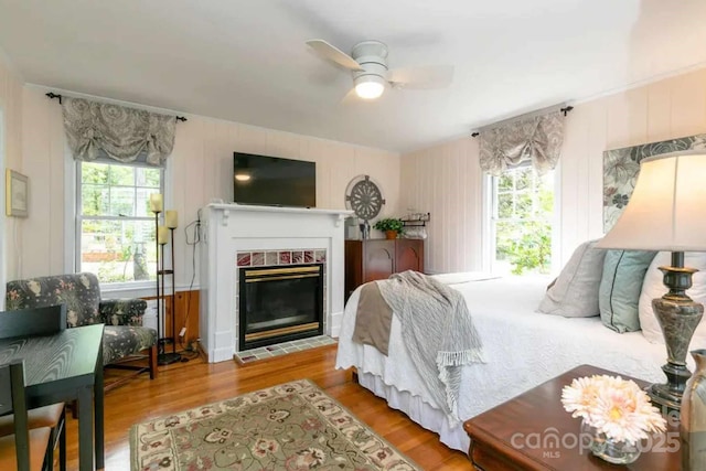 88 S Main St, Weaverville, NC 28787 - bedroom featuring a tile fireplace, ceiling fan, multiple windows, and wood finished floors