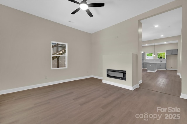 126 Hemphill Ave, Chester, SC 29706 - unfurnished living room featuring dark wood-type flooring, ceiling fan, a glass covered fireplace, baseboards, and recessed lighting