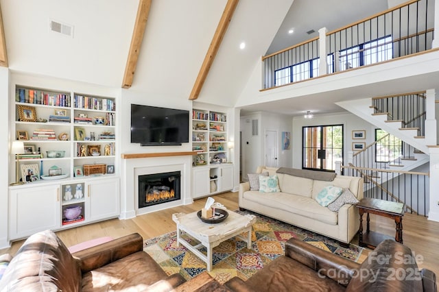 153 High Hills Dr, Mooresville, NC 28117 - living area with wood finished floors, high vaulted ceiling, stairway, a glass covered fireplace, and beamed ceiling