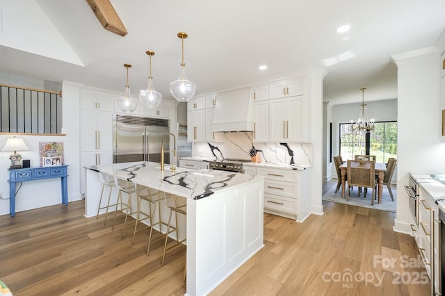 153 High Hills Dr, Mooresville, NC 28117 - kitchen with premium appliances, custom exhaust hood, light wood-style flooring, white cabinets, and a chandelier