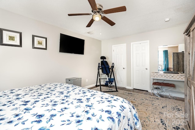 bedroom featuring wood finished floors, multiple closets, baseboards, and ceiling fan