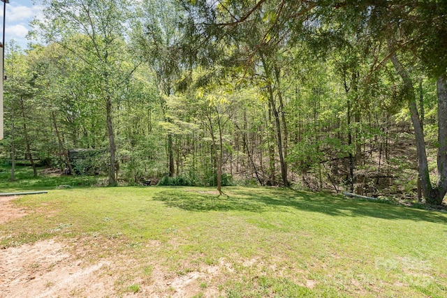 view of grassy yard with a wooded view