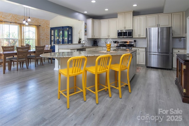 7397 Mill Ruins Ave SW, Concord, NC 28025 - kitchen featuring appliances with stainless steel finishes, decorative backsplash, light wood finished floors, light stone counters, and recessed lighting