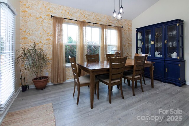 7397 Mill Ruins Ave SW, Concord, NC 28025 - dining room with wallpapered walls, light wood-type flooring, lofted ceiling, and a chandelier