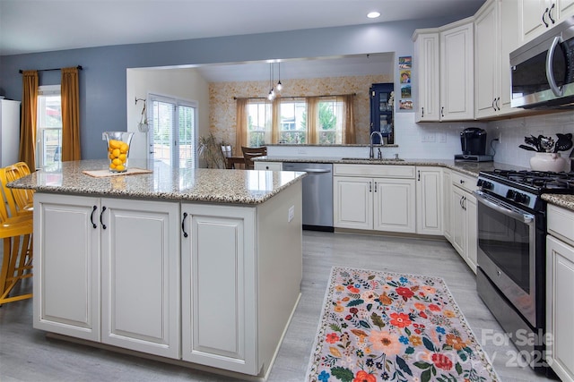 7397 Mill Ruins Ave SW, Concord, NC 28025 - kitchen featuring stainless steel appliances, white cabinets, a kitchen island, light wood finished floors, and backsplash