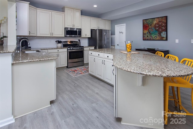 7397 Mill Ruins Ave SW, Concord, NC 28025 - kitchen with stainless steel appliances, light wood finished floors, a breakfast bar, recessed lighting, and light stone countertops