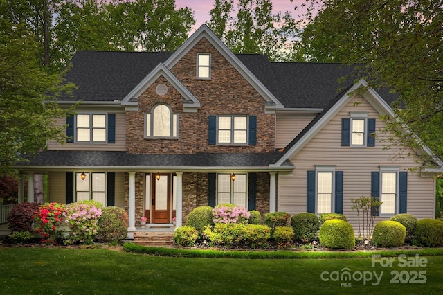 263 Fernbrook Dr, Mooresville, NC 28117 - traditional home with stone siding, a shingled roof, a front yard, and a porch