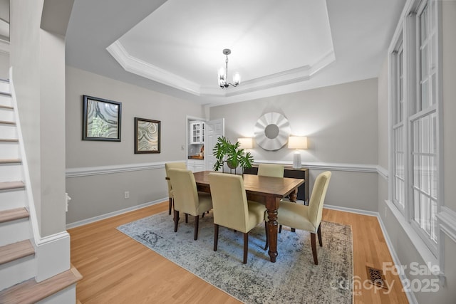 263 Fernbrook Dr, Mooresville, NC 28117 - dining area with a chandelier, stairs, light wood-style floors, a tray ceiling, and baseboards