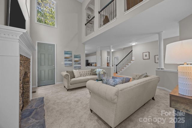 263 Fernbrook Dr, Mooresville, NC 28117 - carpeted living room featuring a towering ceiling, stairway, decorative columns, and baseboards