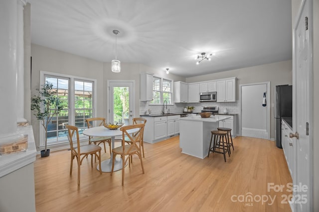 263 Fernbrook Dr, Mooresville, NC 28117 - kitchen with appliances with stainless steel finishes, backsplash, white cabinets, a sink, and a center island