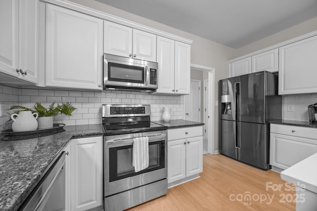263 Fernbrook Dr, Mooresville, NC 28117 - kitchen featuring stainless steel appliances, white cabinets, light wood finished floors, decorative backsplash, and dark stone counters