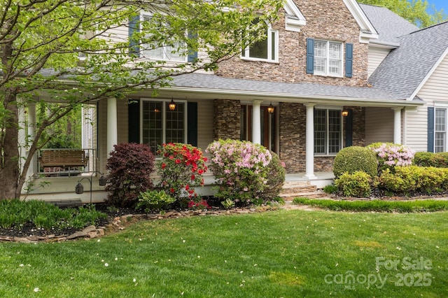 263 Fernbrook Dr, Mooresville, NC 28117 - view of front of home featuring covered porch, a front yard, a shingled roof, and stone siding