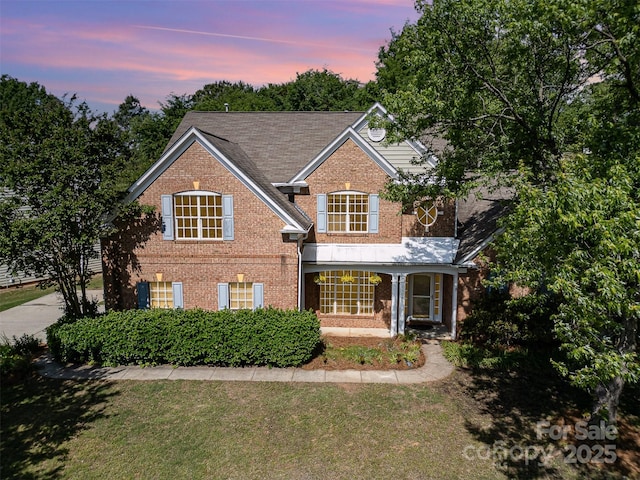 traditional-style house featuring brick siding and a lawn