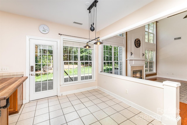 unfurnished dining area with healthy amount of natural light, a glass covered fireplace, and baseboards