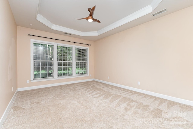 empty room with ornamental molding, a tray ceiling, carpet floors, a ceiling fan, and baseboards