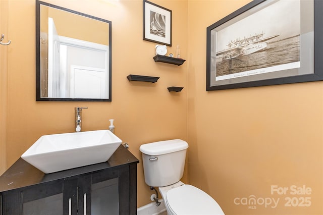 half bath with toilet, vanity, and baseboards