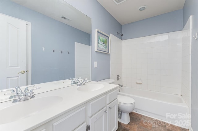 bathroom with toilet, shower / washtub combination, stone finish flooring, and double vanity