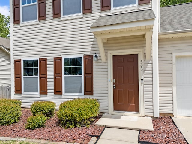 property entrance with a garage and a shingled roof