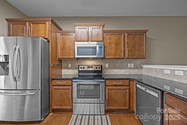 kitchen featuring brown cabinetry, wood finished floors, and stainless steel appliances