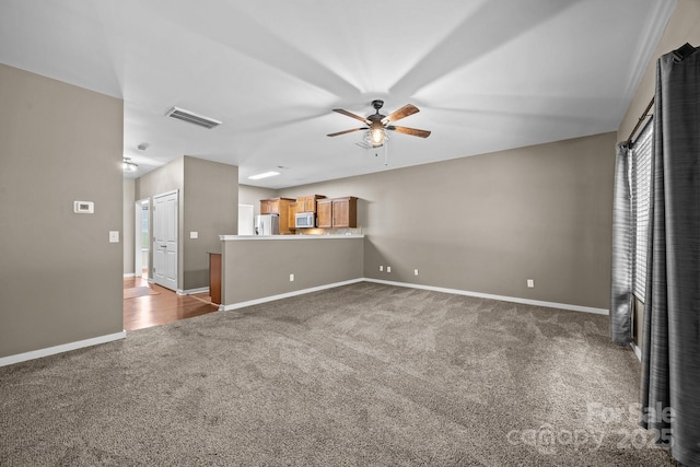 unfurnished living room with baseboards, a ceiling fan, visible vents, and carpet flooring