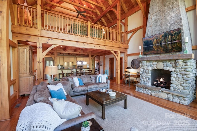 54 Cottage Grove Dr, Nebo, NC 28761 - living room featuring wood-type flooring, arched walkways, high vaulted ceiling, a stone fireplace, and a ceiling fan
