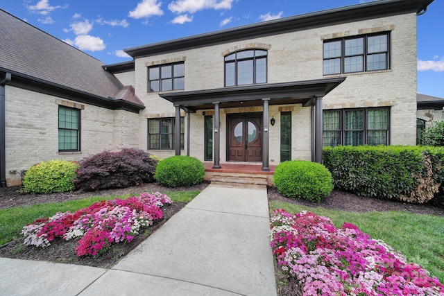 view of exterior entry with brick siding and a porch