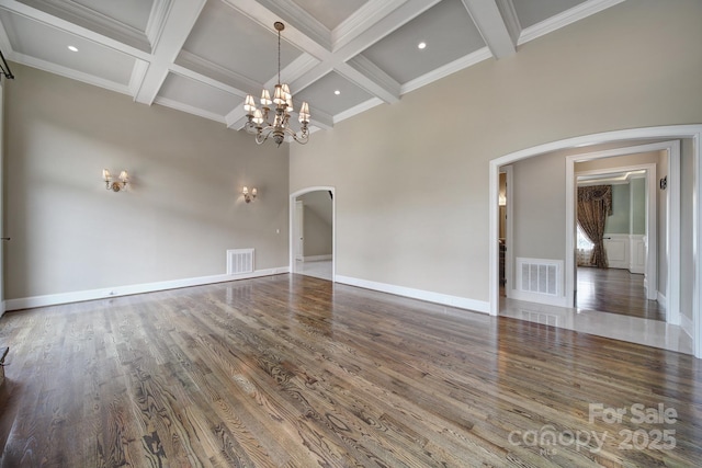 unfurnished living room with wood finished floors, arched walkways, beamed ceiling, a notable chandelier, and visible vents