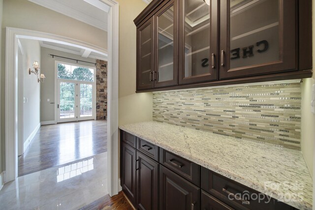 bar with decorative backsplash, beamed ceiling, crown molding, baseboards, and dark wood-type flooring