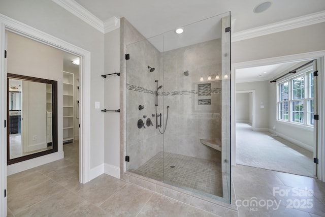 full bath featuring a shower stall, tile patterned flooring, ornamental molding, a walk in closet, and baseboards