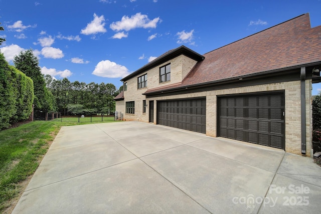 view of property exterior featuring an attached garage, driveway, fence, and roof with shingles