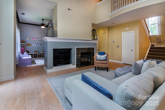 3404 Pasture View Ct, Charlotte, NC 28269 - living room with a tiled fireplace, stairs, ceiling fan, and wood finished floors
