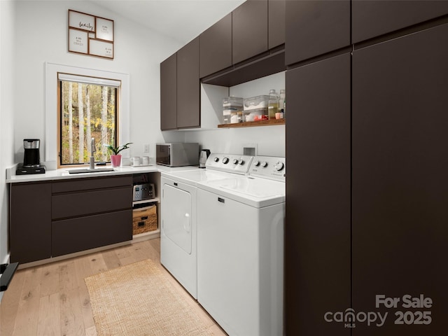 146 Timber Creek Rd, Hendersonville, NC 28739 - laundry area with light wood finished floors, washer and clothes dryer, a sink, and cabinet space