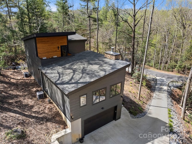 146 Timber Creek Rd, Hendersonville, NC 28739 - view of outbuilding with a wooded view, concrete driveway, and an attached garage