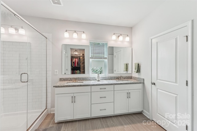 bathroom with visible vents, a sink, double vanity, and a stall shower
