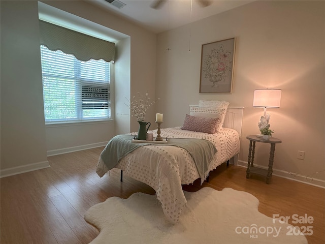 bedroom with wood finished floors, visible vents, and baseboards