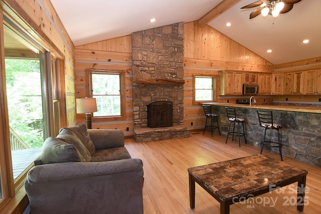 living room with a wealth of natural light, a ceiling fan, wood walls, and light wood-style flooring