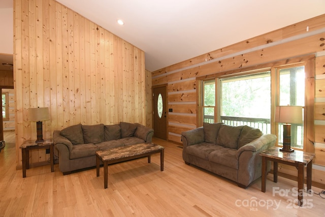 living area featuring light wood finished floors, wood walls, high vaulted ceiling, and recessed lighting