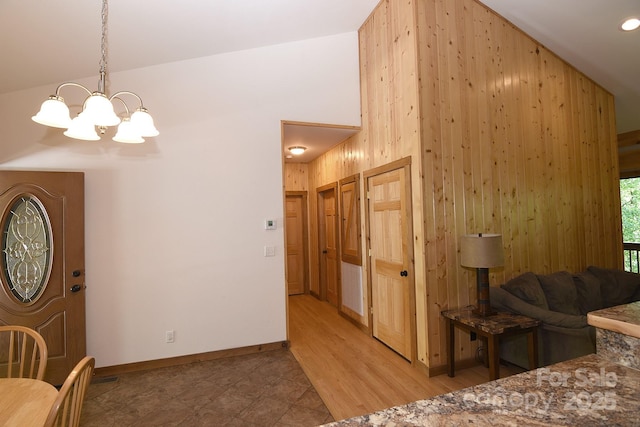 interior space with a chandelier, wooden walls, a high ceiling, and baseboards