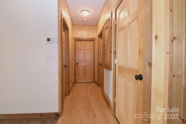 hallway featuring light wood-style flooring and baseboards