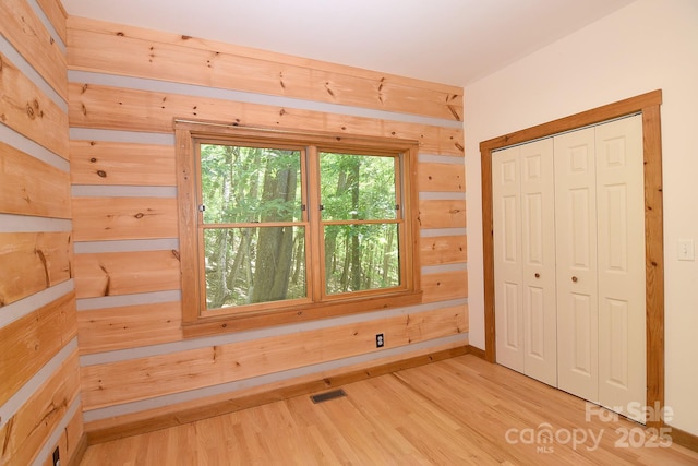 bonus room featuring visible vents, wooden walls, and wood finished floors
