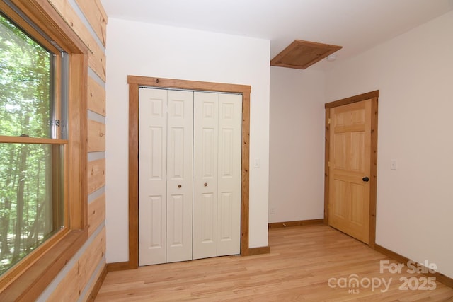 unfurnished bedroom featuring baseboards, a closet, and light wood-type flooring