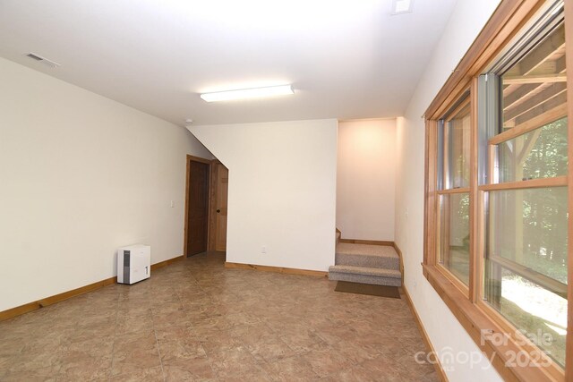 empty room with plenty of natural light, visible vents, baseboards, and stairway