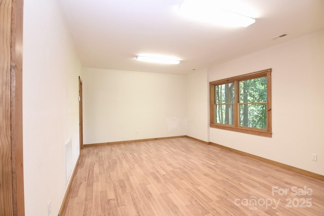 spare room featuring baseboards, visible vents, and light wood-style flooring