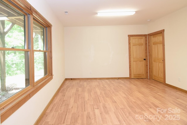 unfurnished room featuring baseboards, visible vents, and light wood finished floors