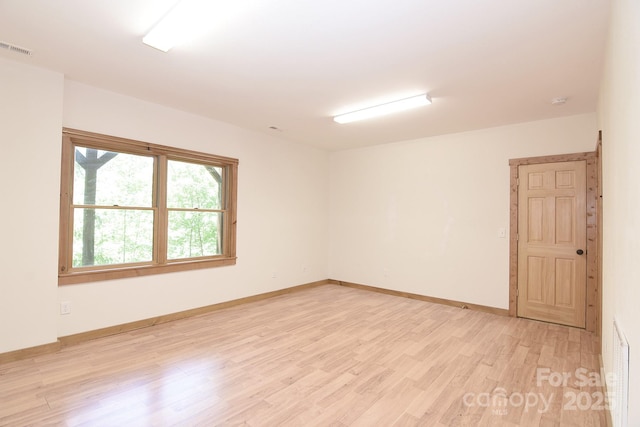 spare room featuring light wood-style floors, visible vents, and baseboards
