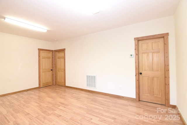 unfurnished room with light wood-style floors, visible vents, and baseboards