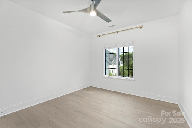 spare room featuring a ceiling fan, baseboards, visible vents, and wood finished floors
