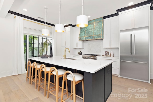 kitchen with stainless steel built in refrigerator, a sink, custom exhaust hood, recessed lighting, and light wood-style flooring