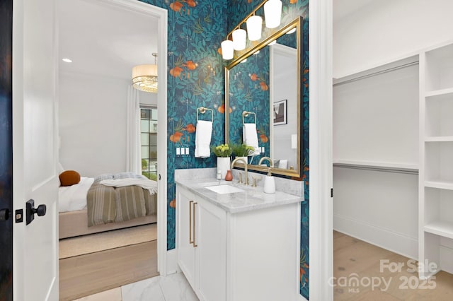 full bathroom featuring vanity, baseboards, wallpapered walls, and ensuite bath