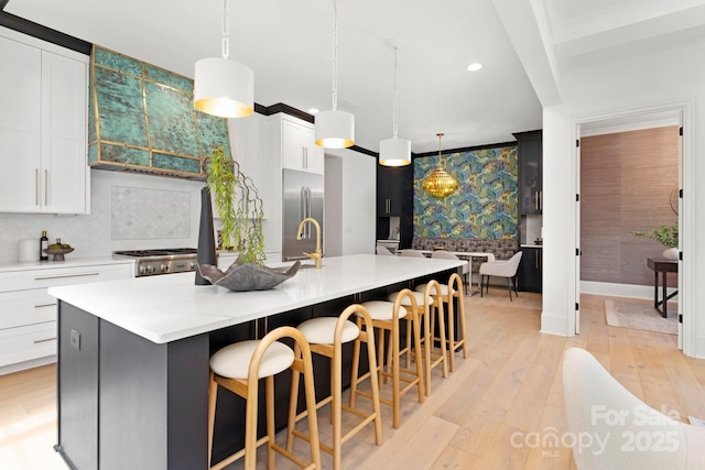 kitchen featuring light wood-style floors, an island with sink, recessed lighting, wallpapered walls, and high quality fridge